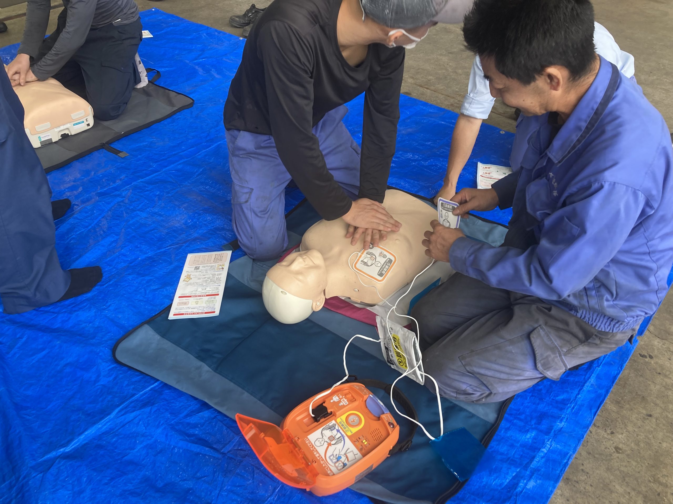 真剣にダミー人形に対しての胸骨圧迫とAEDセット風景